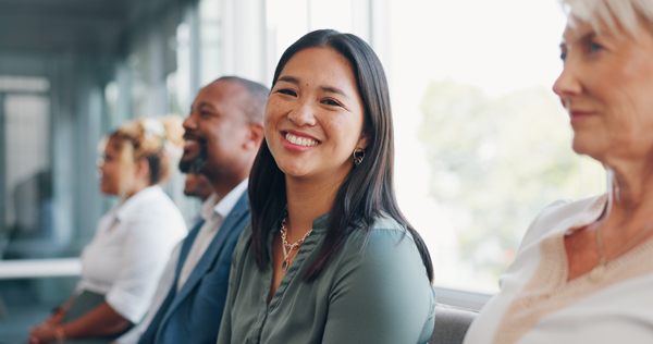 smiling young woman sitting in row of waiting candidates for interview