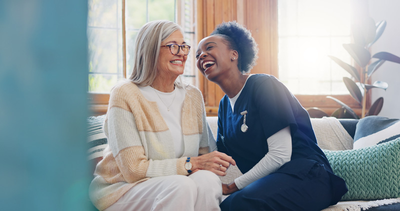 carer and client laughing on sofa together